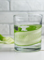 A glass of detox water infused with cucumber and mint, with ingredients. Health care, fitness, healthy food concept.