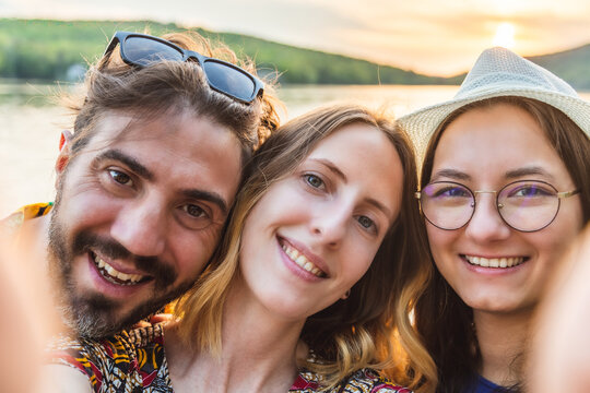 Portraits of three smiling best friends taking a selfie together on vacation. Funny young adults using the phone for selfie. Technology, lifestyle and people concept. 