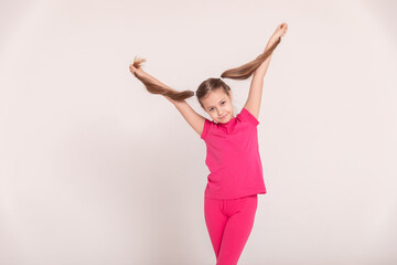 happy child on a white background. a girl in a pink T-shirt and pants.