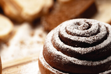 Fresh cinnamon bun roll with sugar powder on wooden board
