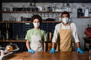 African american baristas in latex gloves and medical masks standing in cafe