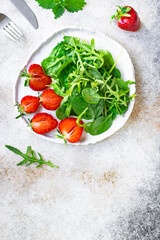 green salad strawberry leaves salad mix arugula, spinach organic healthy food meal snack copy space food background rustic. top view diet vegan or vegetarian food