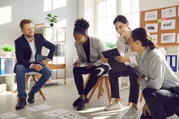 Happy young people developing business strategy in group meeting. Team of office workers analyzing report with financial growth charts and graphs, discussing new project, doing research and having fun