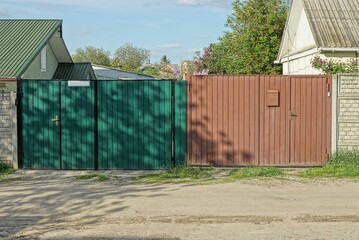 Obraz premium two closed private gates of green and brown metal on the street by the gray road