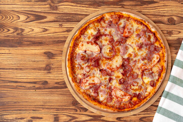 Top view of freshly baked pizza on wooden background