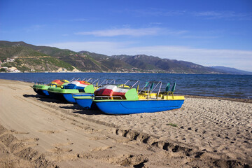 Catamarans boats on a sandy beach in the town of Pogradec against the backdrop of Lake Ohrid - obrazy, fototapety, plakaty