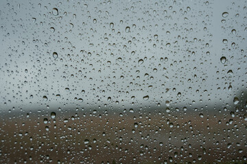 a window covered with raindrops forms an interesting pattern and behind them you can see a foggy landscape