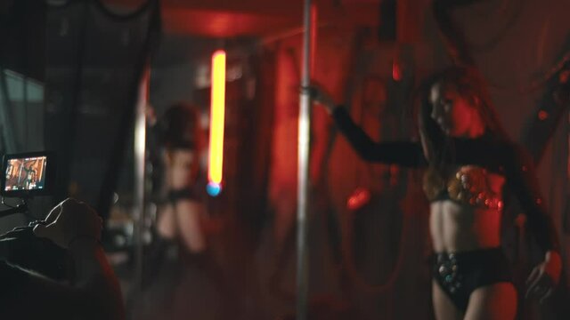 Man with professional camera filming video with sexy woman dancing striptease