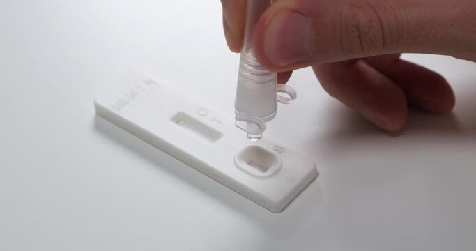 Coronavirus rapid antigen self test strip, placing drops of liquid onto the specimen well on test cassette, Covid-19.