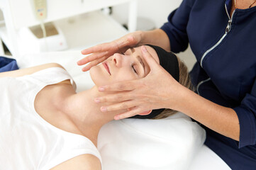 Aeathetician performing professional facial massage on woman face at spa clinic