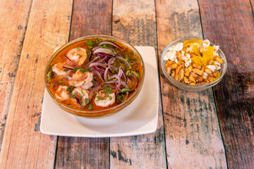 Shrimp ceviche in large quantity in a glass bowl and accompanied by a smaller one full of Peruvian...