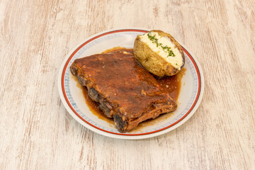 Rack of ribs in barbecue sauce garnished with roasted potato with skin and butter and parsley on top