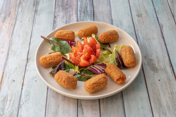 plate of croquettes stuffed with fried chicken with béchamel sauce with sprouts and tomato salad