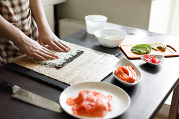 Young teenage boy making maki sushi at home