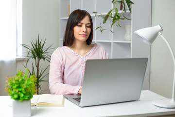 Portrait of a young beautiful woman working on a laptop at home. A Spanish girl student uses a computer to study remotely online.