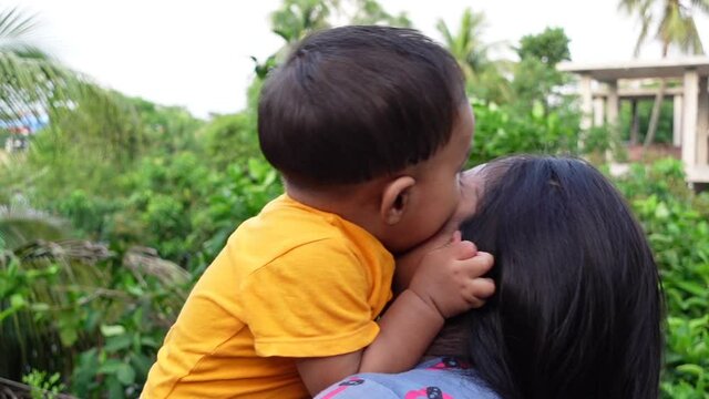 Close up of happy young south Asian mother hugging cuddling little infant. A toddler and mom love smiling. Small baby enjoying the tender family moment. Motherhood and child care concept.
