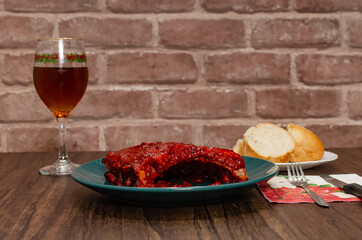 Roasted ribs with barbecue sauce served in a green plate on a wooden plate.