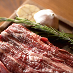 Piece of raw fatty meat with garlic and rosemary. Food cooking concept. Close up shot. Soft focus. Square format.