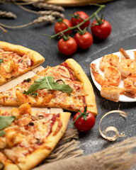 Seafood pizza with prawns. Close up shot. Piece of cutting pizza with shrimps and cherry tomatoes on black table background. Soft Focus.