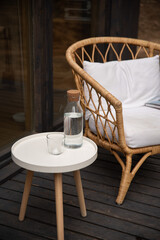 Chair near table with white clean pillow and class of water at the table on terrace in the countryside house.
