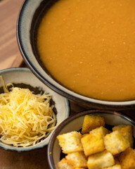 Orange cream soup. Close up. Pumpkin or lentil soup garnished with grated cheese and croutons. Vertical format. Soft focus.