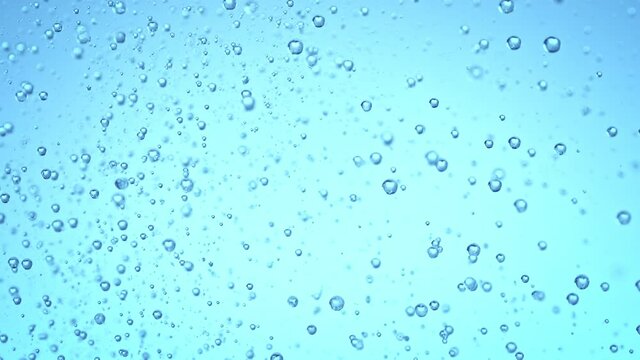 Super Slow Motion Shot of Rising Various Bubbles in Water on Light Blue Background at 1000 fps.