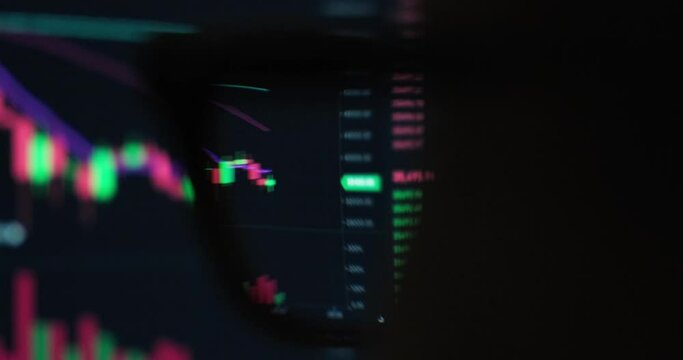 Soft focus view through eye glass lens of person at monitor with live prices updates of crypto currency, online trading platform, investing concept.