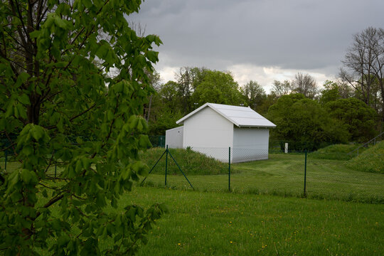 in the green field is a small white building with a fence around