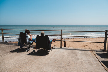 People enjoy the sunny day at beautiful sand beach in East England with wooden beach huts