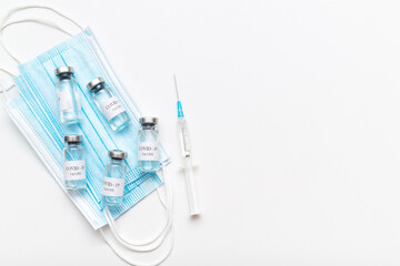 Bottle with coronavirus vaccine on medical masks and medical syringe. protection against Covid-19...