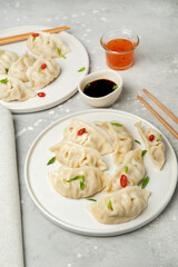 Jiaozi gyoza dumplings steamed on white plates with soy sauce and chili sauce. Food takeaway, home delivery