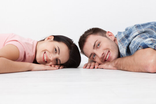 Happy young couple lying on the floor, looking and smiling