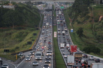 Fototapeta premium Carros em movimento pela Dutra, com um fundo deslumbrante de paisagem, criando um cenário dinâmico e impressionante.