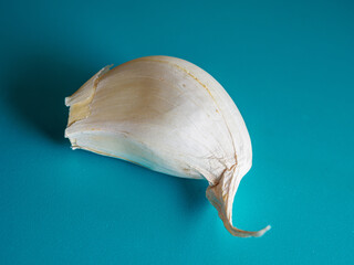 Fototapeta premium Top view of a garlic clove on a turquoise surface