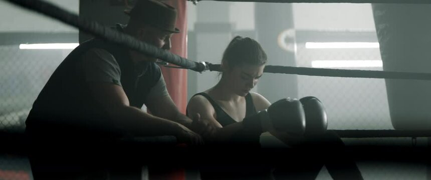 HANDHELD Trainer giving instructions to a female boxer fighter during a fight sparring intermission. Shot with 2x anamorphic lens