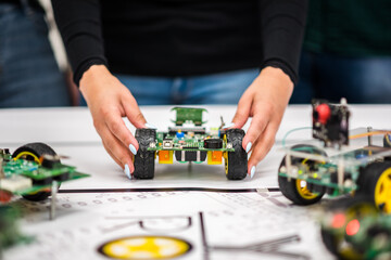 A mechatronic robot with artificial intelligence on wheels thrown by a woman's hands on a table with a canvas.