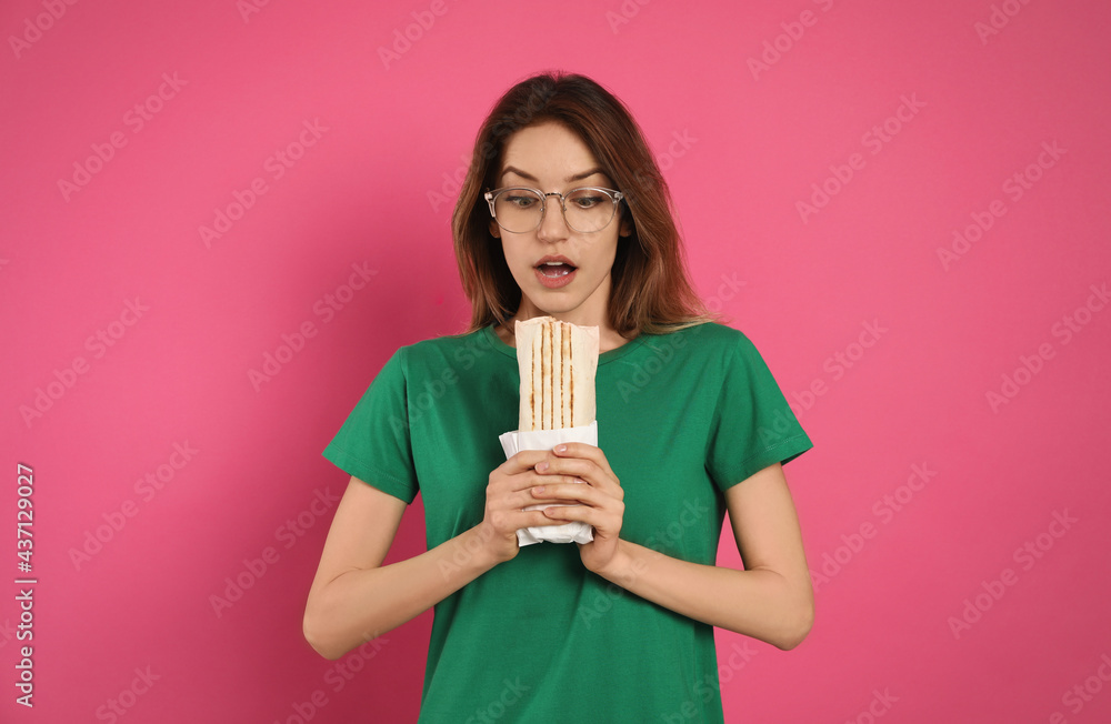 Wall mural emotional young woman with delicious shawarma on pink background