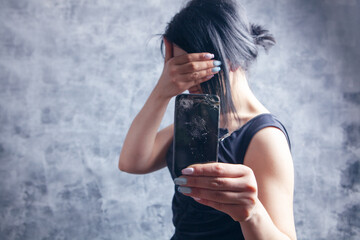 woman showing broken phone covering her face