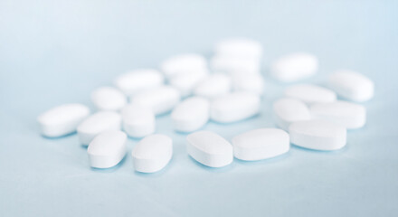 Fototapeta na wymiar White pills on a light blue background. Healthcare and medicine. 
