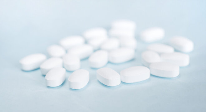 White pills on a light blue background. Healthcare and medicine.	