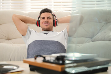 Happy man listening to music with turntable at home