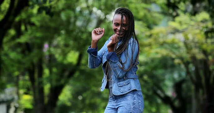 One Happy African woman dancing outside in joy. Person dances celebrating success
