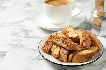 Tasty cantucci and cup of aromatic coffee on white marble table, space for text. Traditional Italian almond biscuits