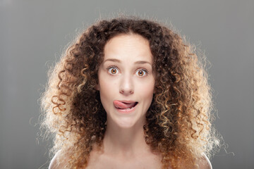 Beautiful girl with long curly hair portrait. Surprised expression with tongue out