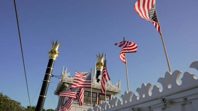 This slow motion video shows a row of American flags flying on top of an old steam boat.