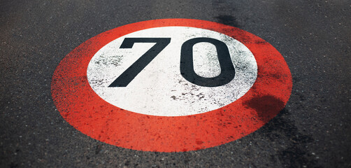 Top view of 70 km per hour, speed limit sign painted on dark asphalting road. Perspective concept.