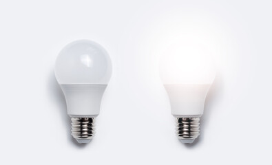 Close-up of two light bulbs with one glowing against white background. Business idea concept.