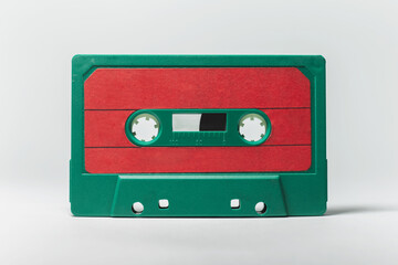 Obraz premium Close-up of green-red vintage music cassette on white background. Studio object image.