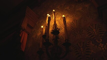 This video shows creepy old antique candle sconce flickering on a dark old plantation mansion wall.