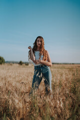 Naklejka na ściany i meble Chica joven atractiva posando en mitad de un campo de trigo al atardecer con tonos dorados